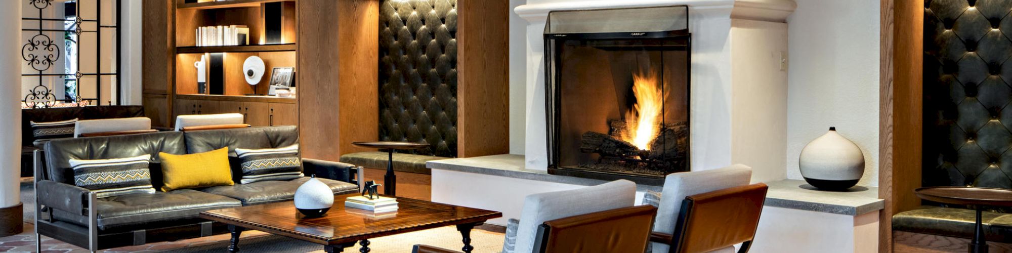 A cozy and modern living room with a fireplace, bookshelves, armchairs, a sofa, and decorative items creating an inviting atmosphere.