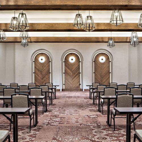 A grand interior with arched windows, ornate columns, and classical seating&mdash;an elegant, sunlit hall.
