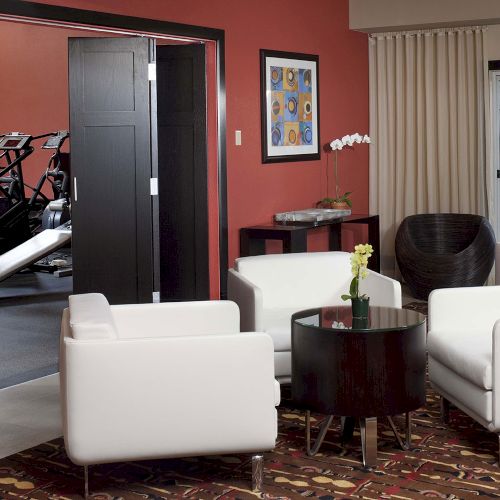 A modern living room with a black-and-white color scheme, white sofa, dark coffee table, and a large TV wall next to floor-to-ceiling windows.