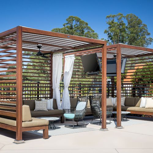 A wooden pergola and deck with seating, plants, and a shaded patio area. Top it at 140 characters, always ending the sentence.