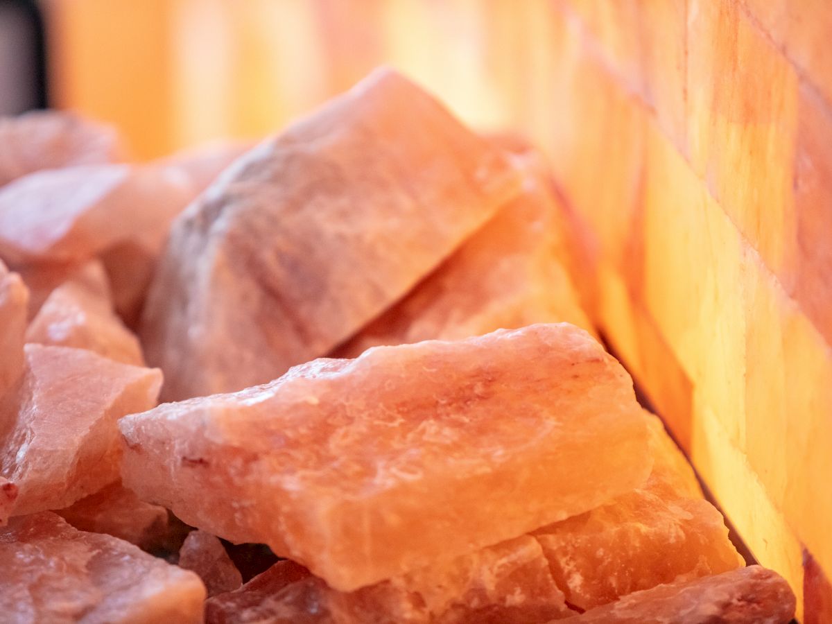 The image shows a close-up of Himalayan salt blocks and rocks illuminated by a warm light source, creating a cozy atmosphere.