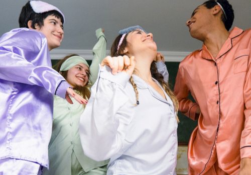 Four people in colorful pajamas are happily dancing together in a room, looking joyful and lively.