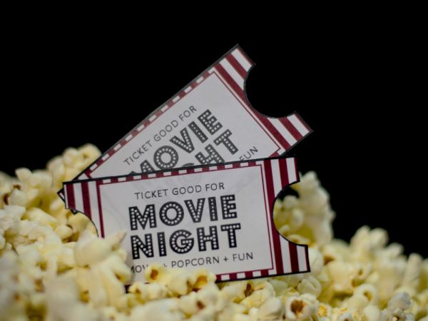 Two movie-night tickets perched in popcorn kernels, inviting a cozy cinema vibe.