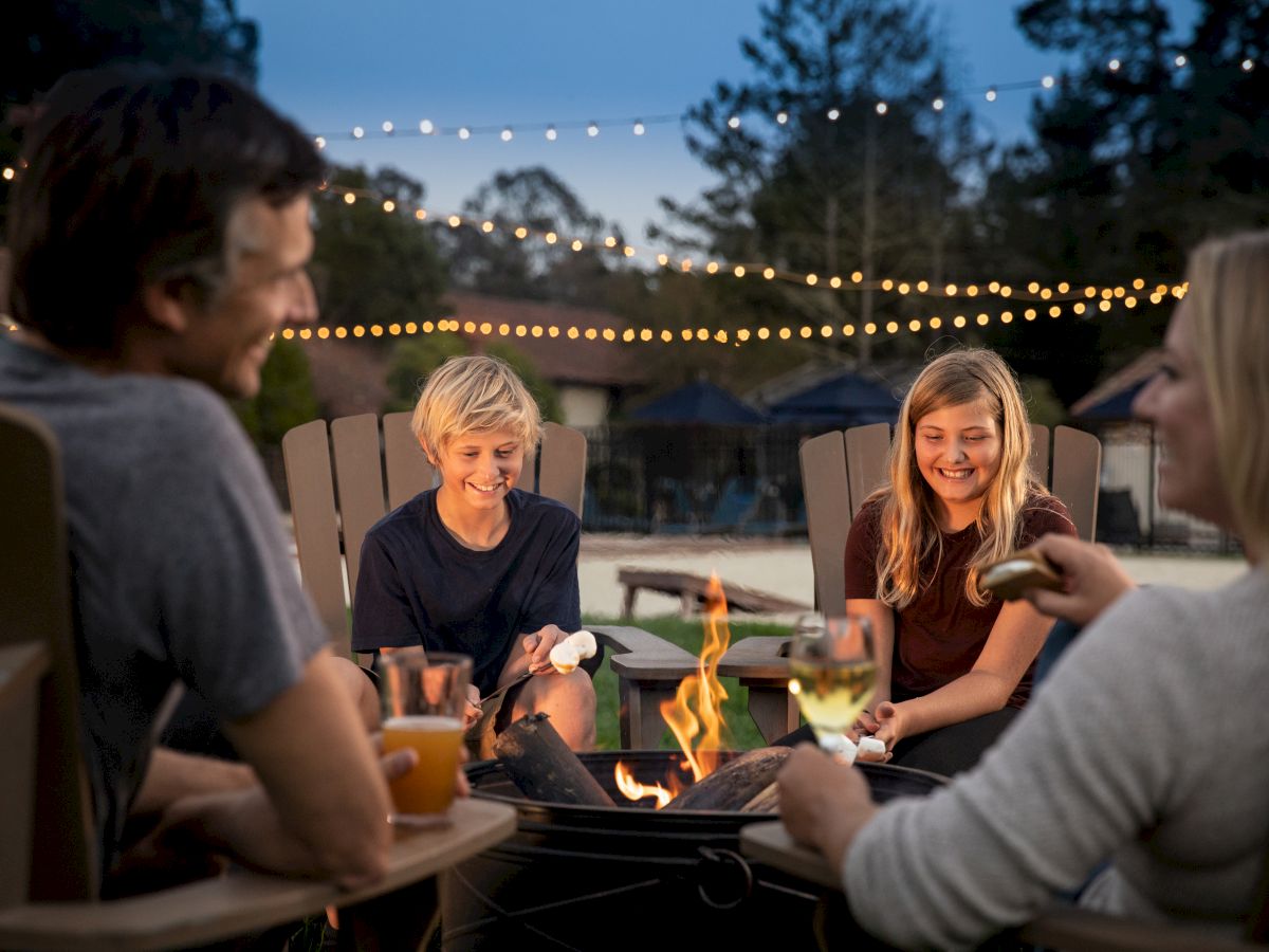 A group of friends around a fire pit, chatting and laughing under string lights at dusk, drinks in hand and a cozy outdoor vibe.